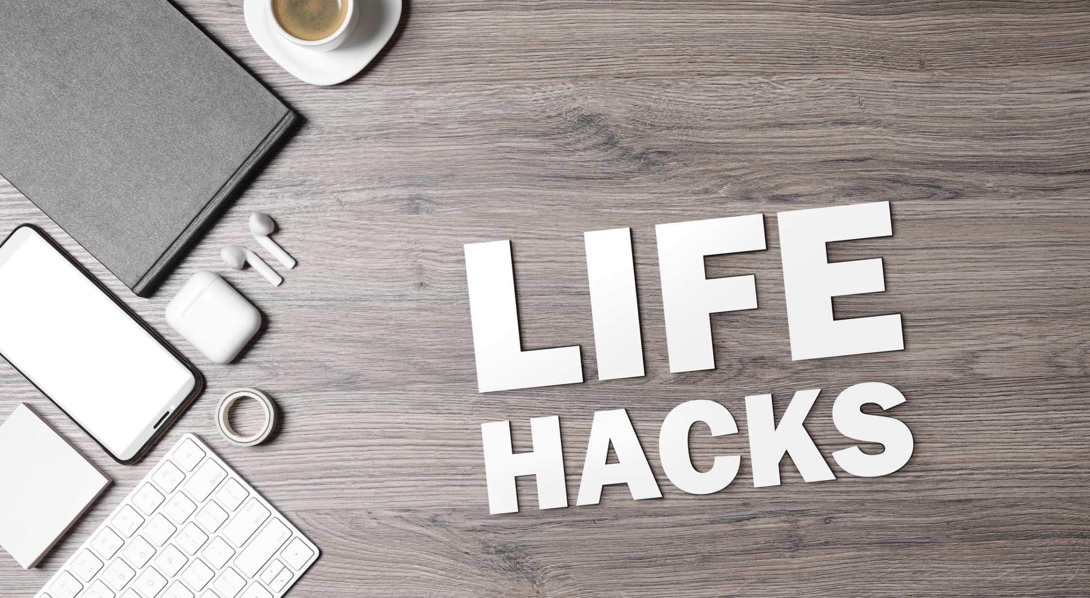 Schreibtisch mit einen Iphone, Notizbuch, Kopfhörer, tastertur, Tasse Kaffe & Haftnotizen. Das Wort Lafestyle Hacks ist zu lesen